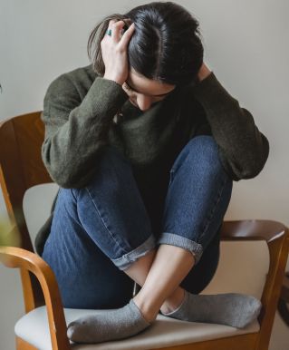 Anxious young woman cover wing ears with hands sitting on chair