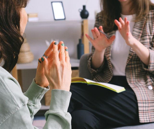 Crop unrecognizable female psychologist and patient discussing mental problems during session